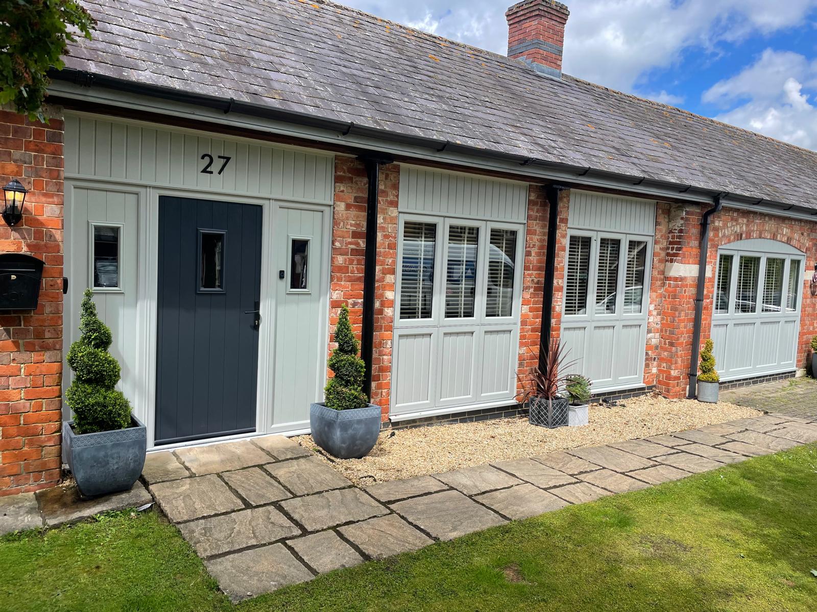 Sage green flush casement windows and anthracite composite front door on a brick barn conversion in Rutland
